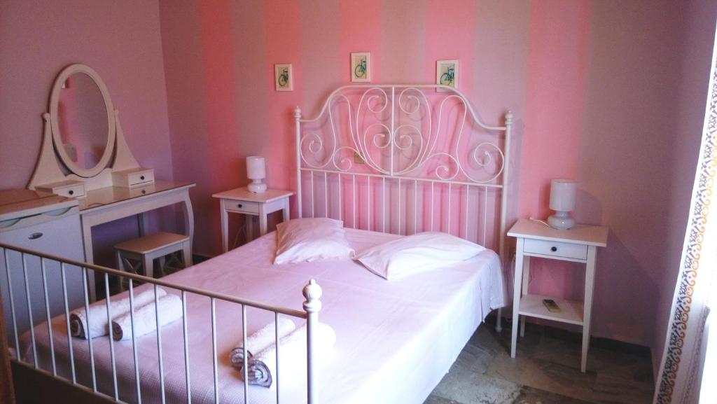 Un dormitorio con una cama blanca con paredes rosas y un espejo en Studios Lefkada, en Sívros