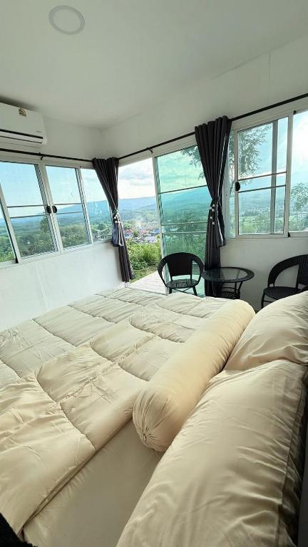 two large beds in a room with large windows at ภูโอบตะวันรีสอร์ต - Phu Oab Tawan Resort in Nan