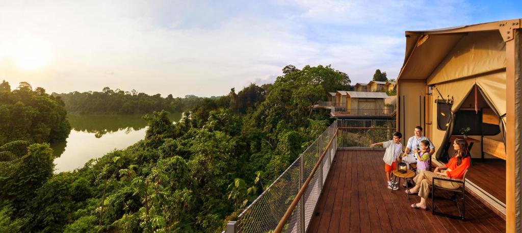 a group of people standing on a deck overlooking a river at Colugo Camp, Mandai Wildlife East in Singapore