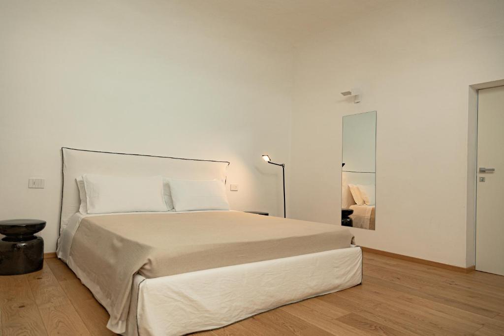 a white bedroom with a large bed and a lamp at Palazzo Console in Lecce