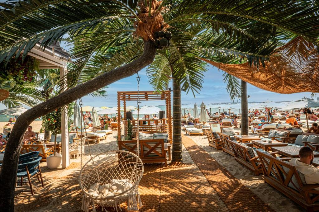 a beach with tables and chairs and palm trees at Sunny Beach Vila in Sunny Beach
