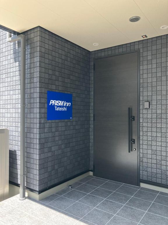 Una puerta en un edificio con un cartel. en PRISM Inn Tateishi, en Tokio
