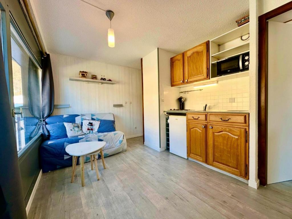 Una sala de estar con un sofá azul y una cocina. en Edelweiss Résidence plein centre de la station rez de chaussée 50 m des navettes gratuites belle terrasse et grand parking privé en sous sol, en Les Carroz d'Araches