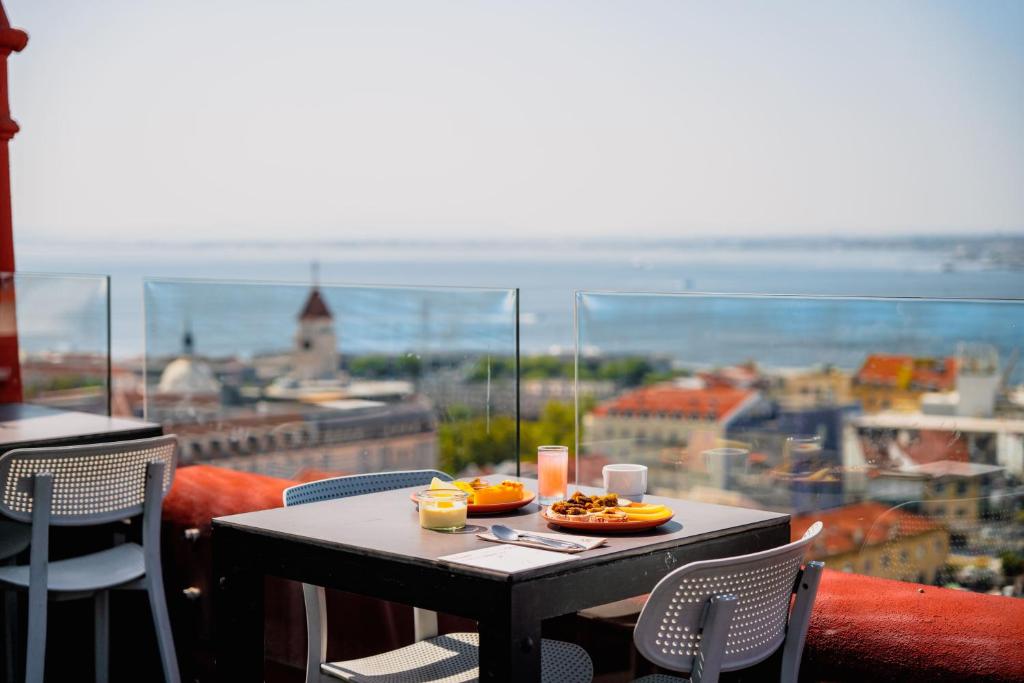 a table with a plate of food on top of a balcony at Monte Belvedere Hotel by Shiadu in Lisbon