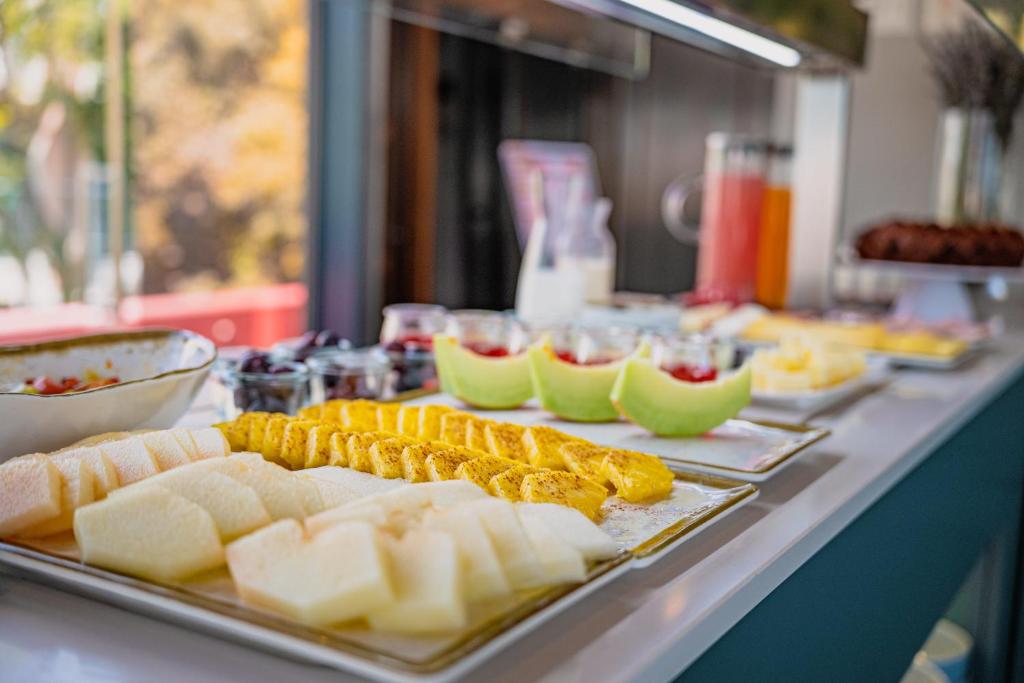 A buffet counter displaying cut fruit, cheese and drinks.
