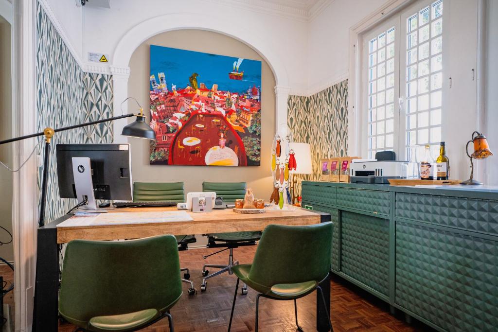 A stylish shared workspace with a long wooden desk, monitor and green chairs.