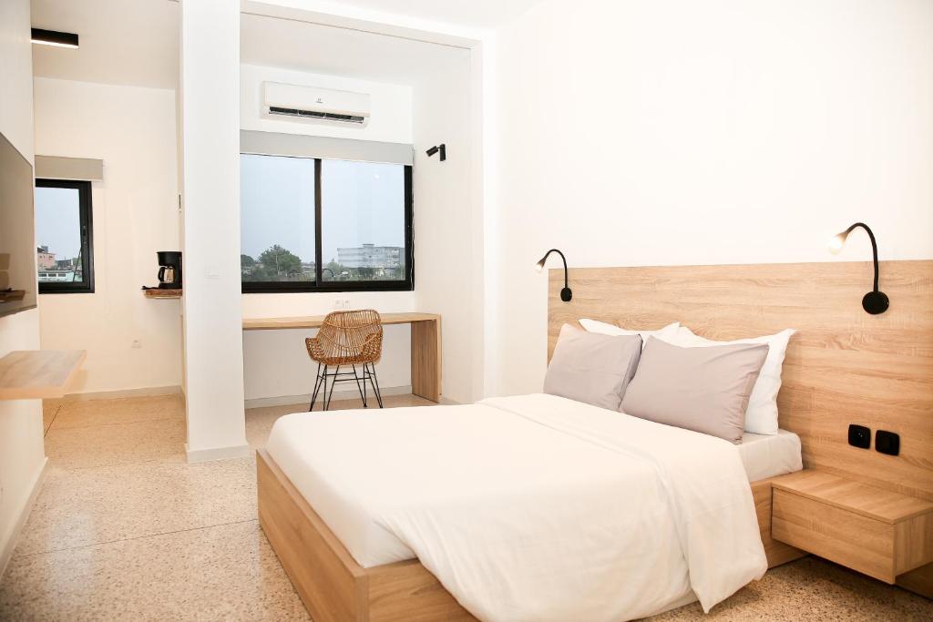 a bedroom with a white bed and a desk at Innoplaza Cocody in Abidjan
