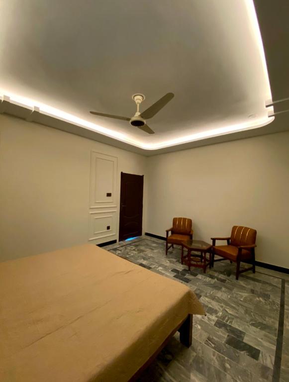 a room with two chairs and a ceiling fan at Well furnished Room in Apartment in Rahimyar Khan