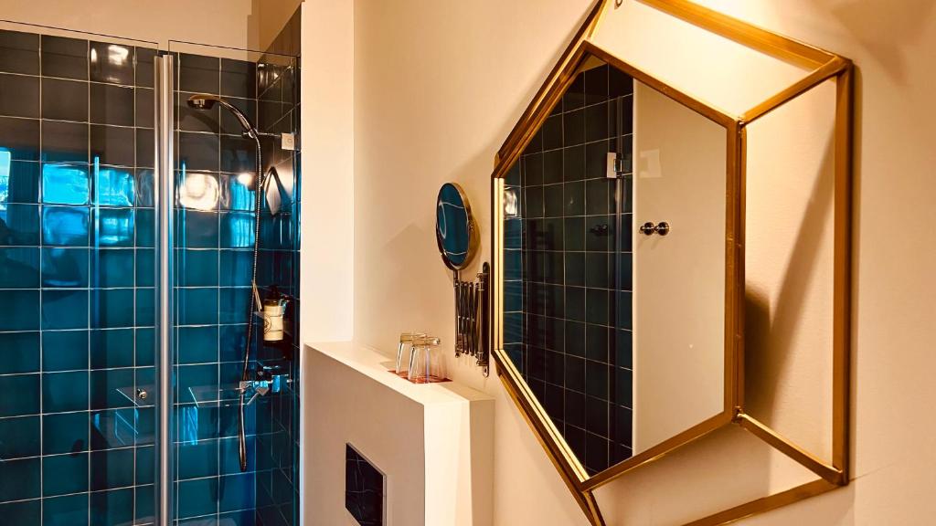 A compact bathroom pairs a white basin with a large geometric mirror and a blue-tiled shower.