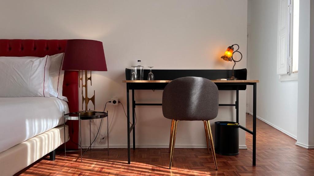 A bedroom workspace with a long desk, upholstered chair and compact refreshment setup.