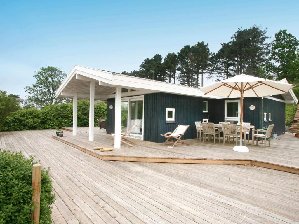 a house with a deck with a table and an umbrella at 6 person holiday home in Dronningmølle-By Traum in Hornbæk
