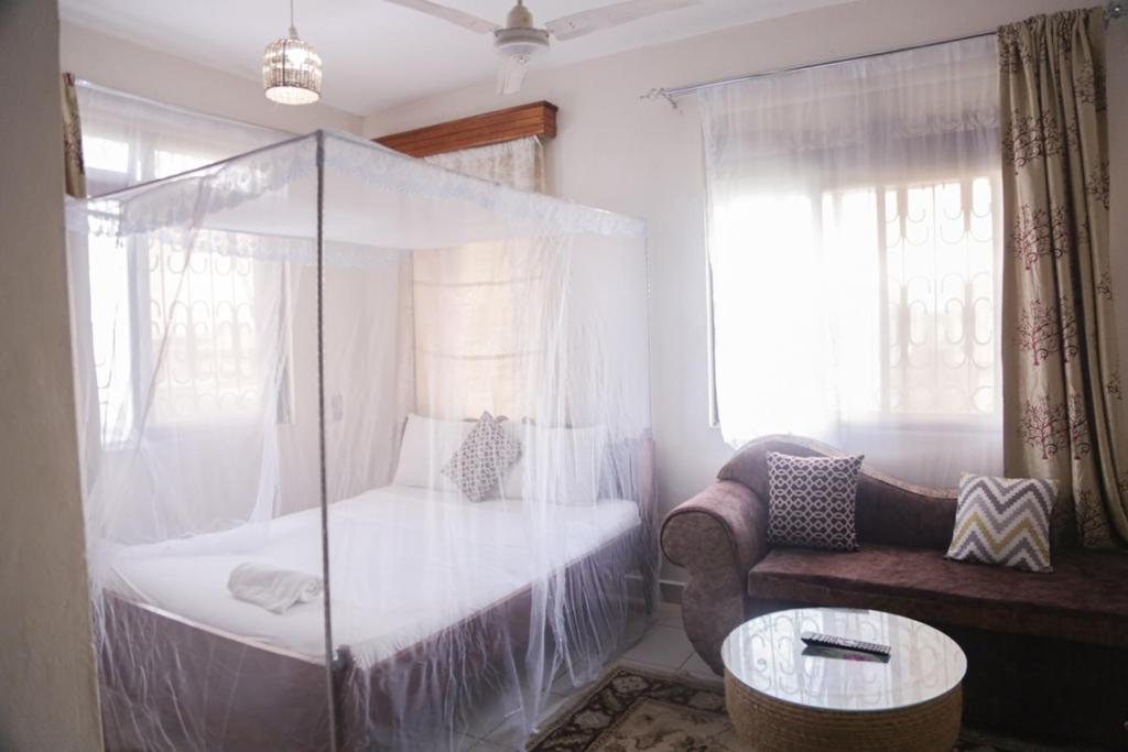 a bedroom with a canopy bed and a couch at Truthvacay in Mombasa