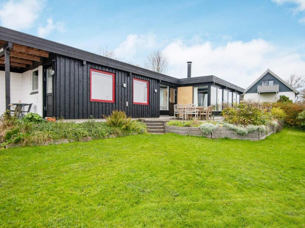a black house with red windows and a yard at 6 person holiday home in Børkop-By Traum in Børkop