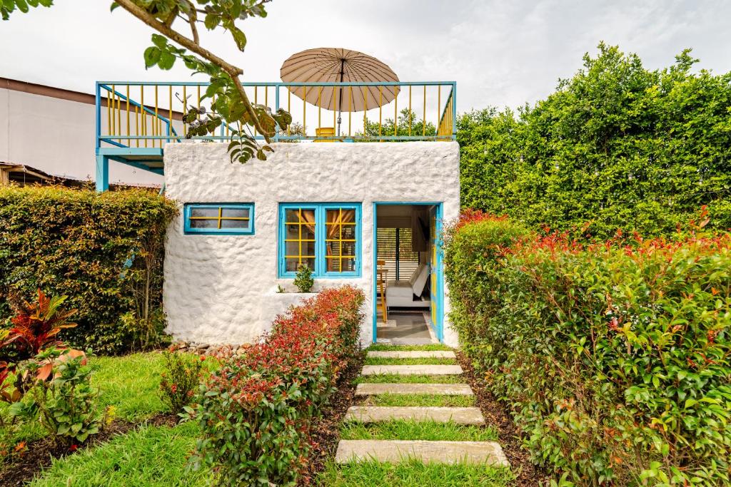 a small house with a blue door in a garden at La Morena - Hospédate en una finca cafetera tradicional in Pereira