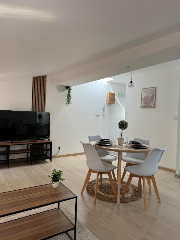a living room with a table and chairs and a tv at Appartement Garibaldi cosy - bien placé & tout confort in Saint-Étienne