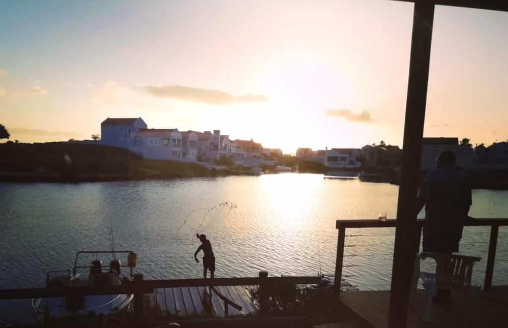 a person is standing on a boat in the water at Skoenlapper holiday home in Velddrif