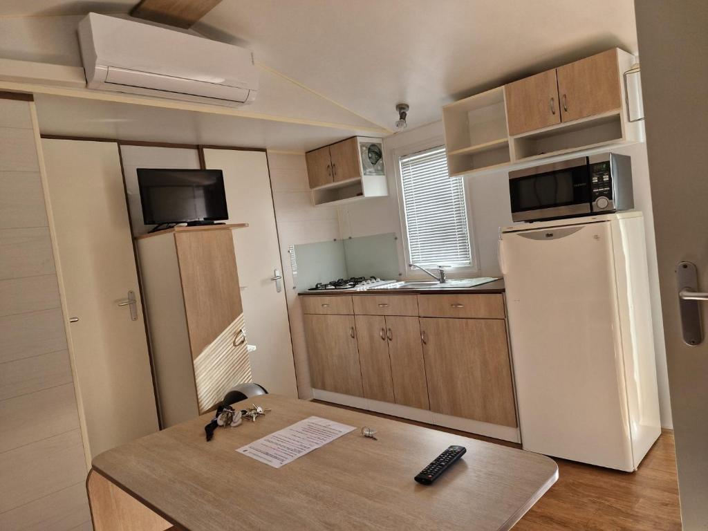 Cabrières-dʼAiguesにあるCamping Onlycamp Les Chênes Vertsのテーブルと冷蔵庫のある小さなキッチン