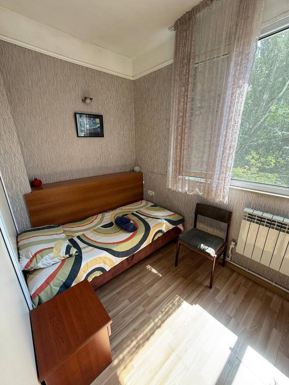 a bedroom with a bed and a chair and a window at Cozy Central Room with Terrace in Yerevan