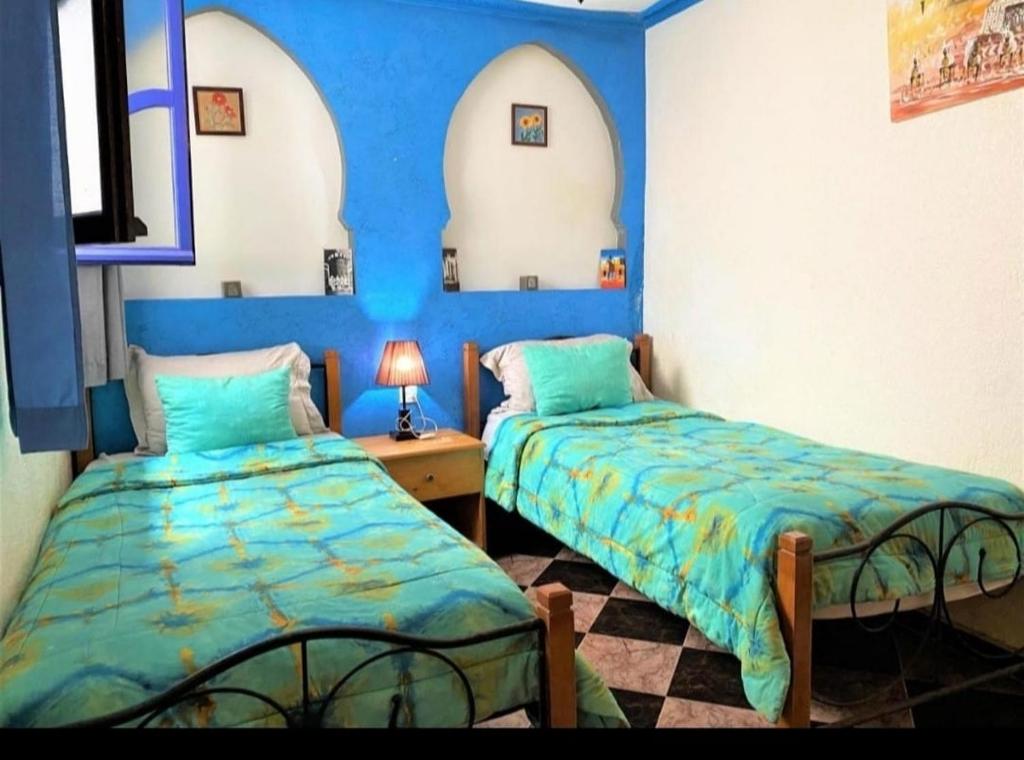 two beds in a room with blue walls at étage 1 avec terrasse et vue sur mer in El Jadida