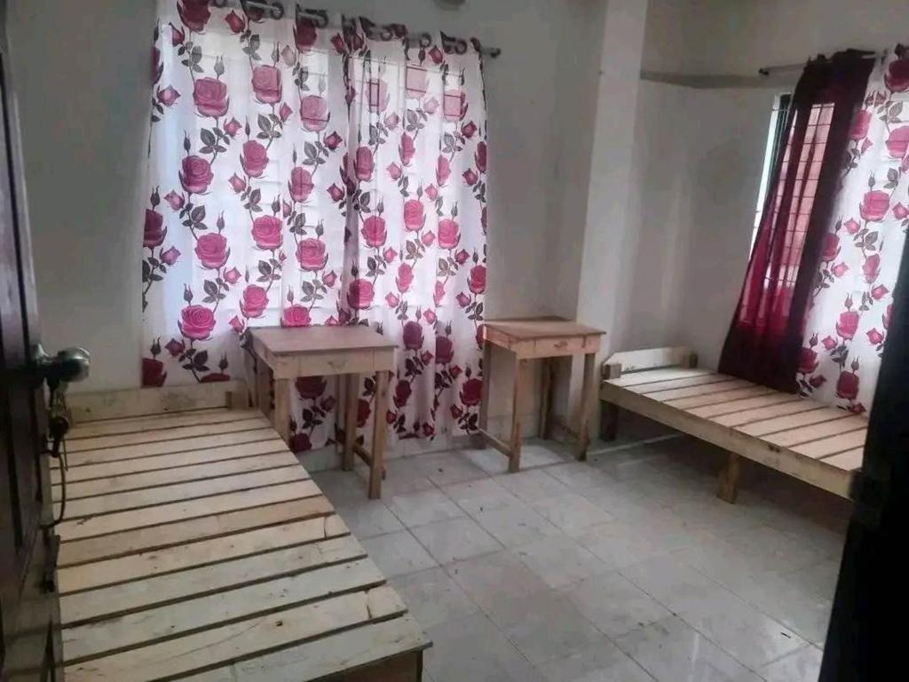 a room with benches and a curtain with pink flowers at Matrichaya Hostel in Dhaka