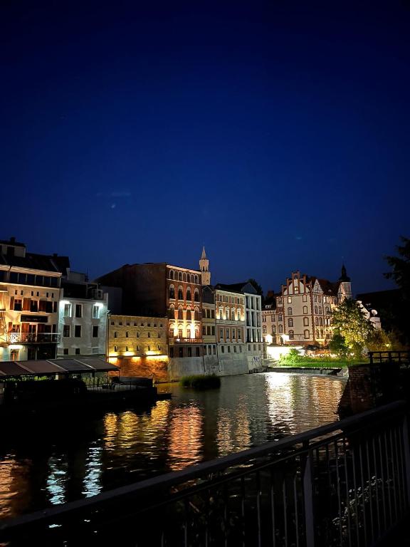 a city at night with a river and buildings at OPOLSKA WENECJA-apartament typu STUDIO z tarasem in Opole