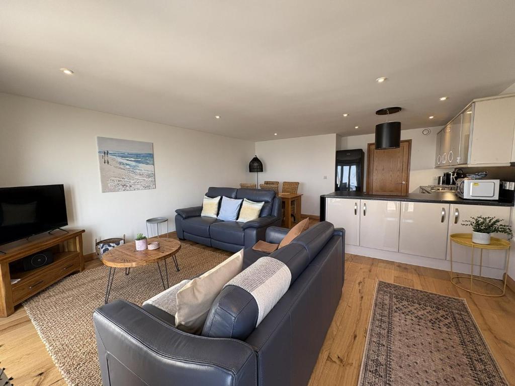 a living room with a couch and a kitchen at Mi Casa Su Casa - Mount Brioni in Downderry