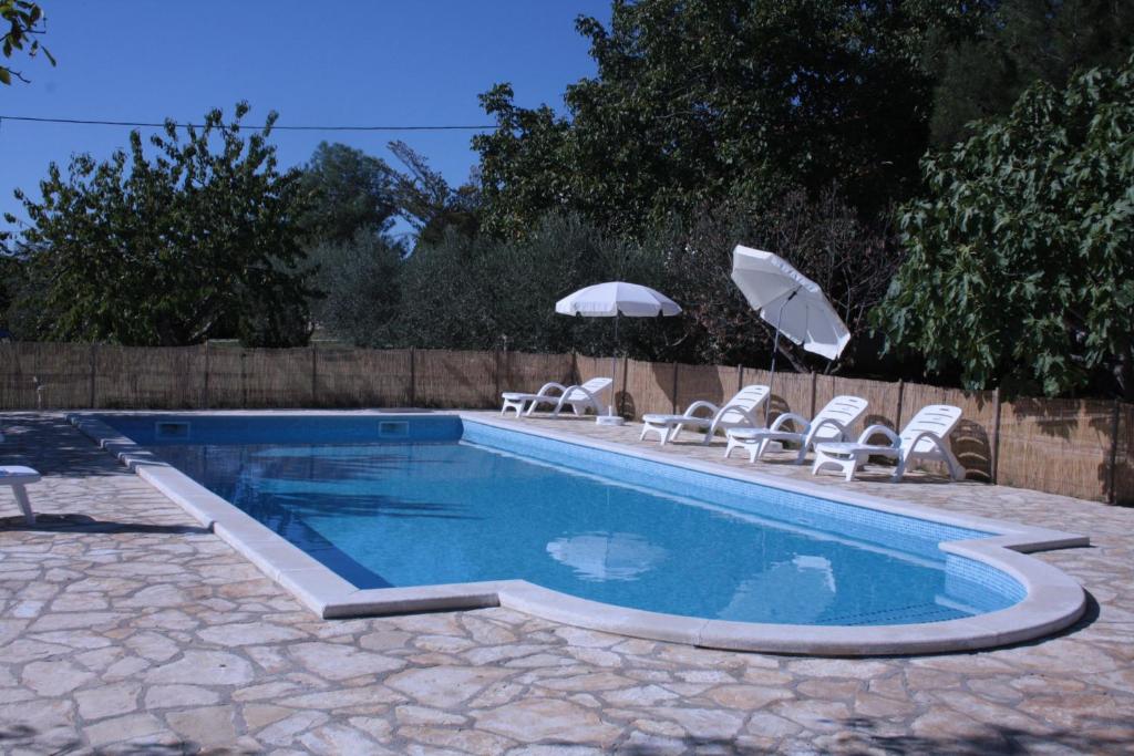 a swimming pool with chairs and umbrellas next to a fence at Sanja apartments Sveti Servul in Novigrad Istria
