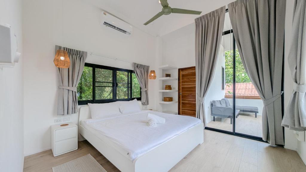 a white bedroom with a bed and a window at Haad Yao Villa 31 in Haad Yao