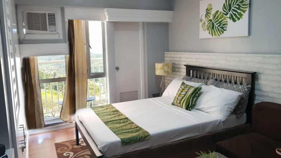 ein Schlafzimmer mit einem Bett und einem großen Fenster in der Unterkunft PRIME CITY LAND Residences Tagaytay in Iruhin