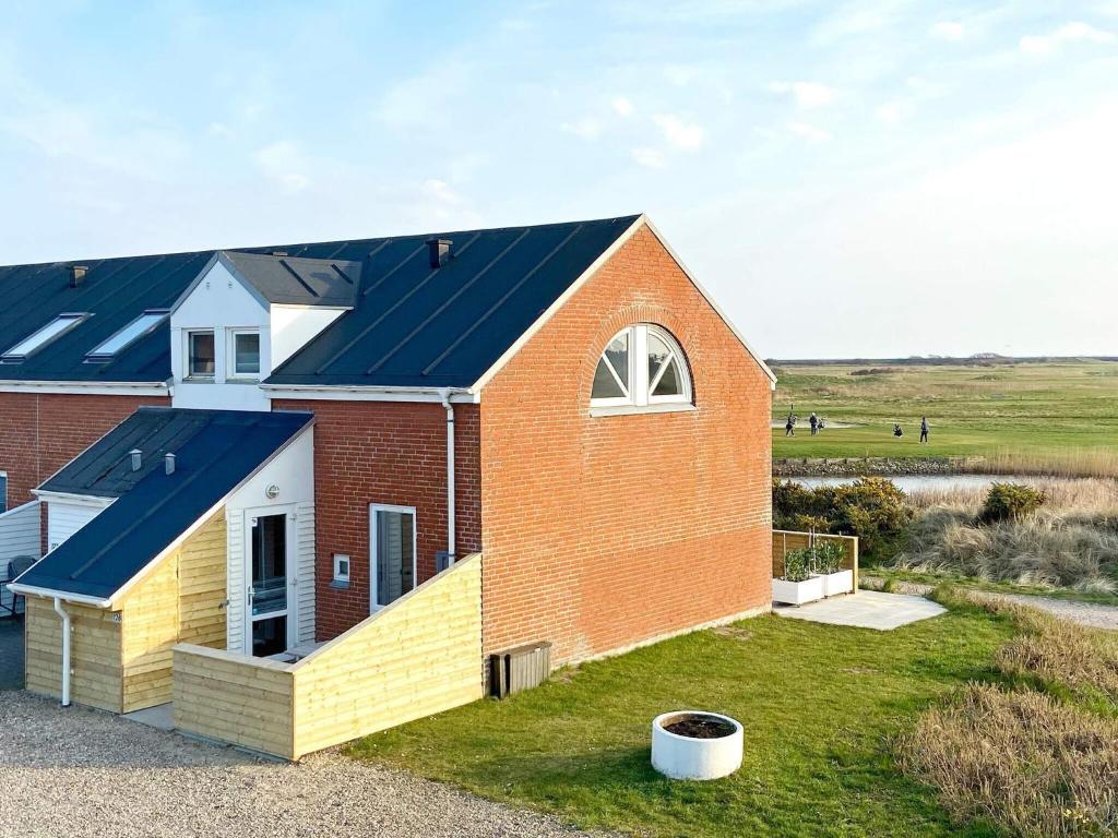 a red brick house with a blue roof at Golf View Retreat - By Traum Ferienwohnungen in Rømø Kirkeby