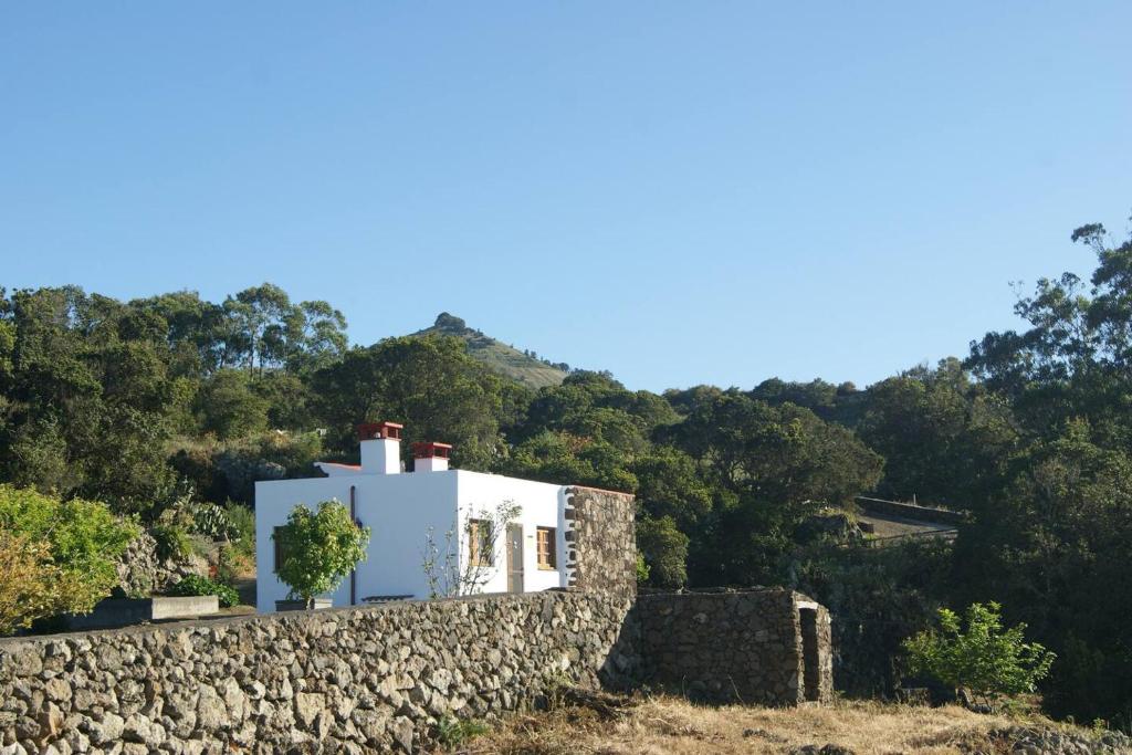 a white house with a stone wall and trees at Casas del Monte in Valverde