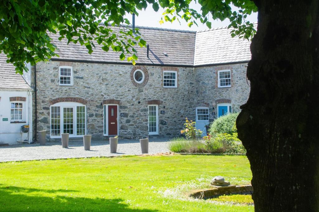 an old stone house with a grass yard in front of it at Stylish Cottage I Hot Tub I Garden I Near Beach in Holyhead