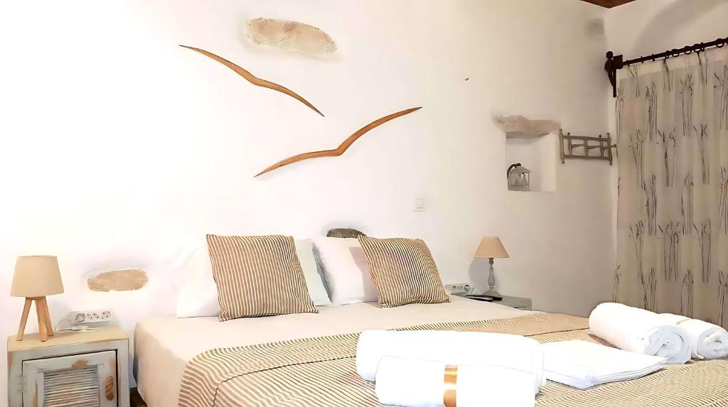 two beds in a white room with birds on the wall at Paros Heritage Retreat by ΜΡS in Parikia