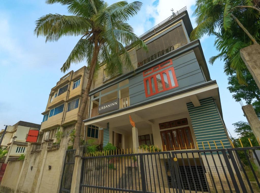 a building with a palm tree in front of it at Urban Inn Rukminigaon in Guwahati