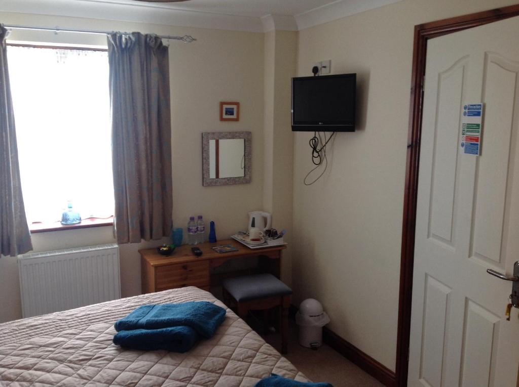 Dormitorio con cama, escritorio y TV en Tregatherall Lodge en Boscastle