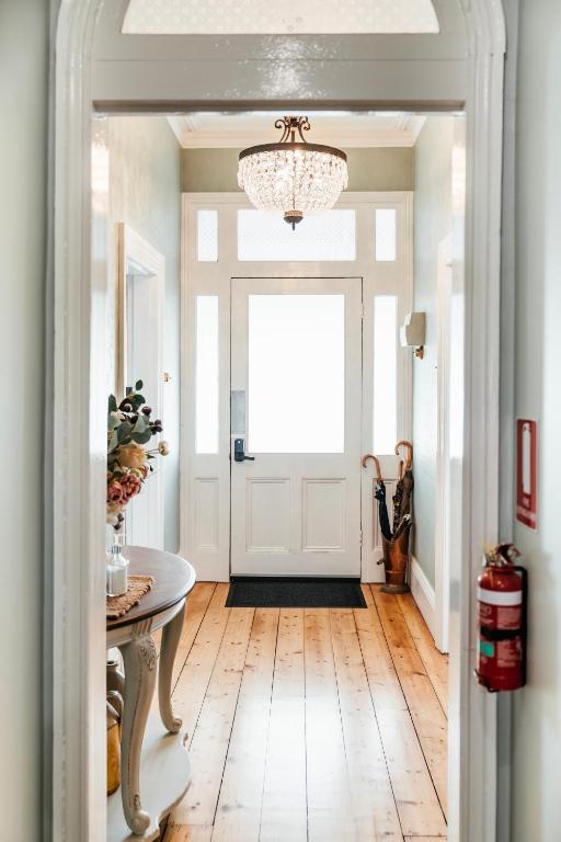 a hallway with a white door and a chandelier at Historic Benambra Boutique Hotel Queenscliff c1883 in Queenscliff