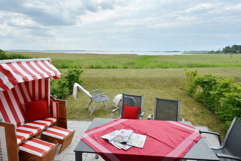 eine Terrasse mit einem Tisch und Stühlen und Blick auf ein Feld in der Unterkunft Ferienhaus Boddenzauber in Breege