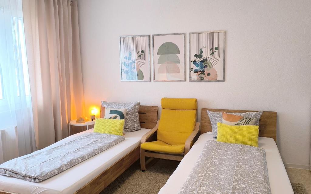 1 dormitorio con 2 camas y silla amarilla en Apartment E - feel good, en Leipzig