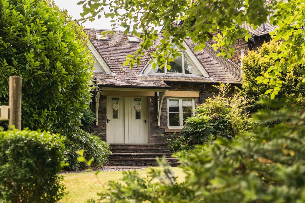 una piccola casa con una porta bianca e alberi di Elterwater Cottage a Windermere