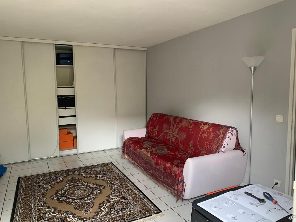 ein Wohnzimmer mit einem roten Sofa und einem Teppich in der Unterkunft Quiet in Poissy city center for work or family stay in Poissy