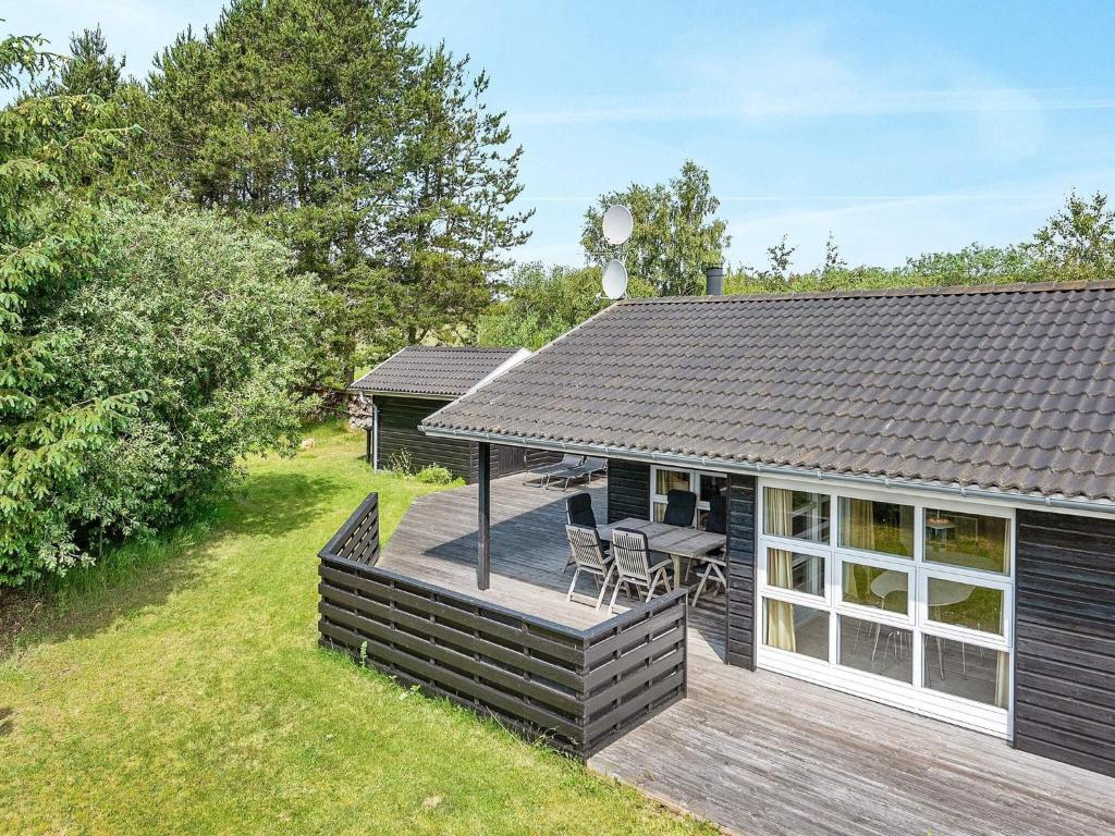 a wooden deck with a table and chairs on a house at 4 star holiday home in Ålbæk in Ålbæk