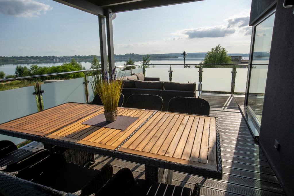 a wooden table on a deck with a view of the water at Ferienhaus SUNFLOWER am Hainer See in Kahnsdorf