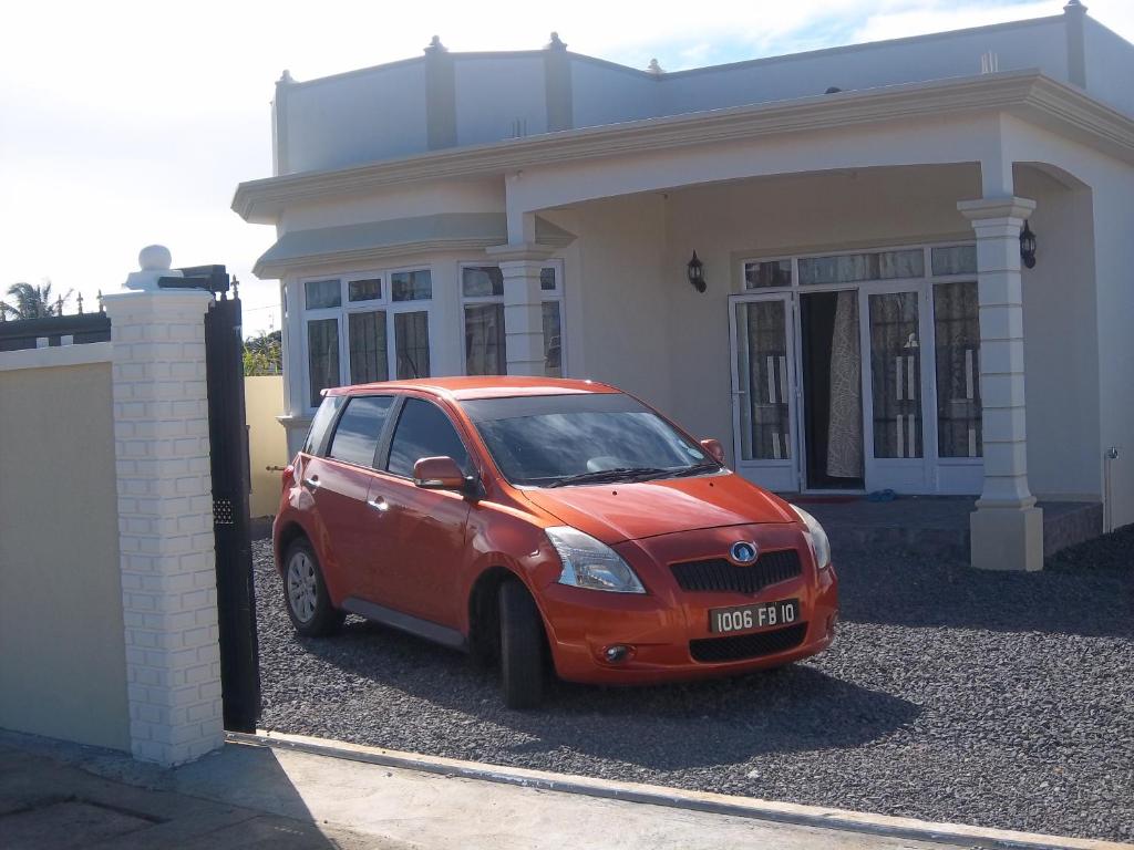 a small red car parked in front of a house at Kaz Resident in Plaine Magnien