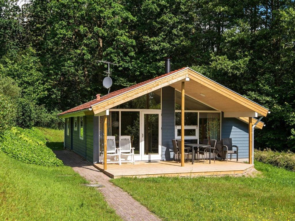 a small green cabin with a deck in the grass at 6 person holiday home in Børkop-By Traum in Egeskov