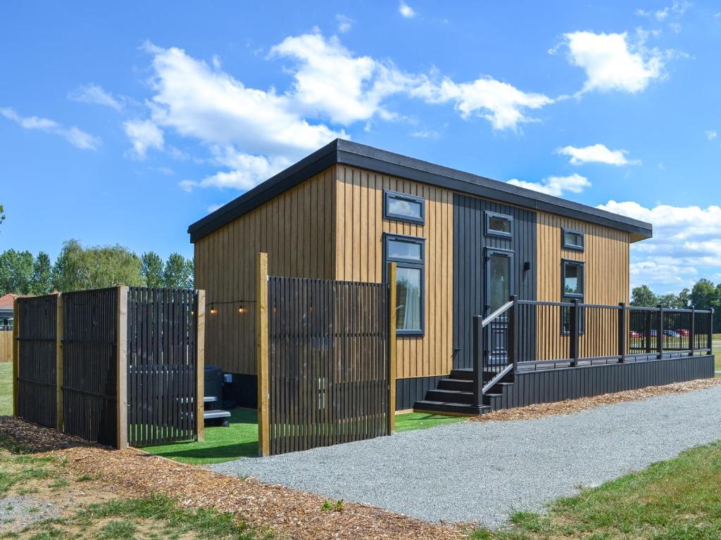 a small wooden house with a black fence at Fairways Retreat 2 - Uk50247 in Cottingham