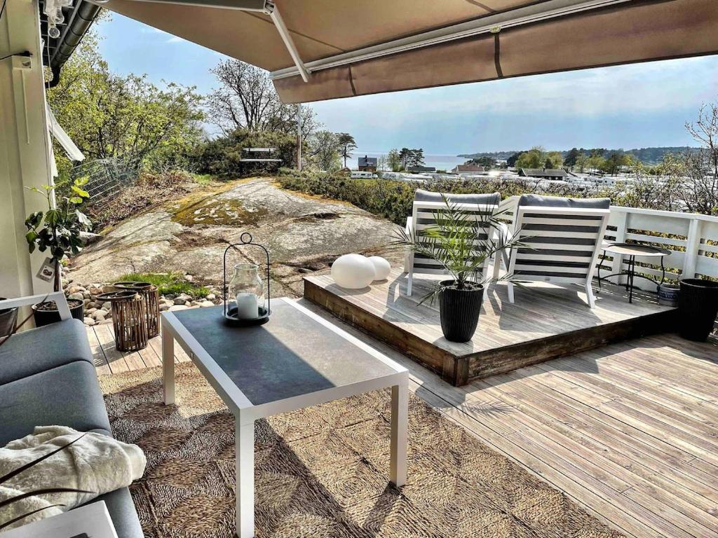 eine Terrasse mit Tisch und Stühlen auf einem Deck in der Unterkunft Stavern Cottage with sea views near the beach in Larvik