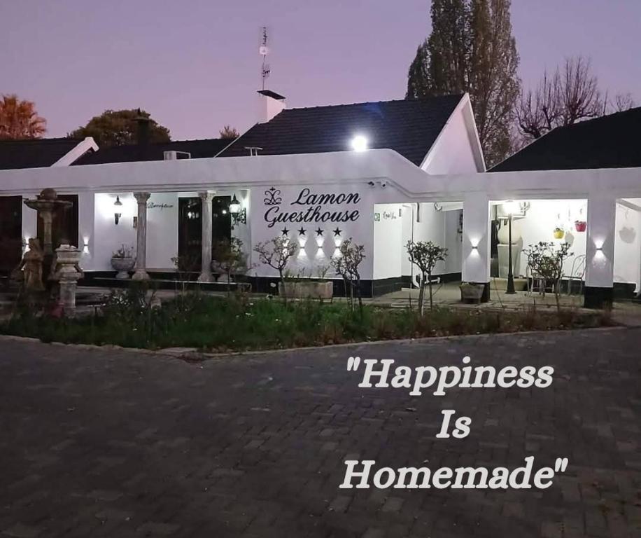 a building with a sign that reads happiness is homogeneous at Lamon Guesthouse in Kroonstad