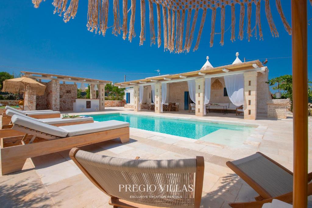 a villa with a swimming pool and a house at I Trulli del Tarassaco with private pool by Pregio Villas in Martina Franca