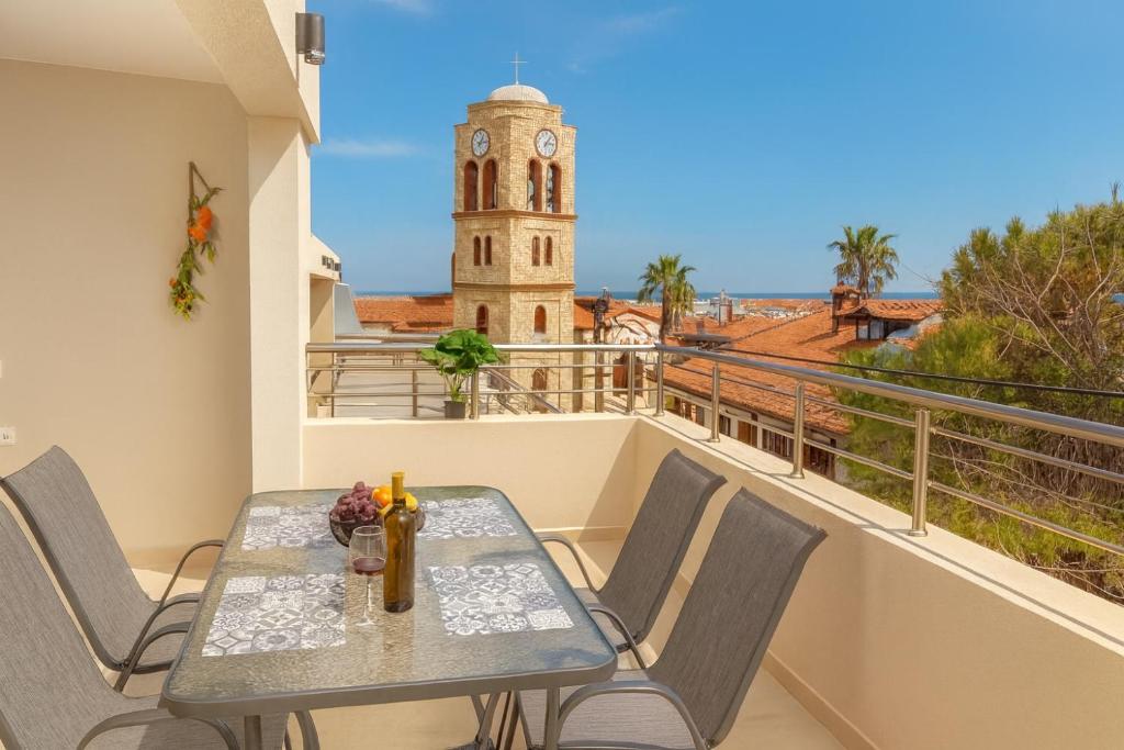 a table and chairs on a balcony with a clock tower at Fortaleza Rooms Pefkochori in Pefkochori
