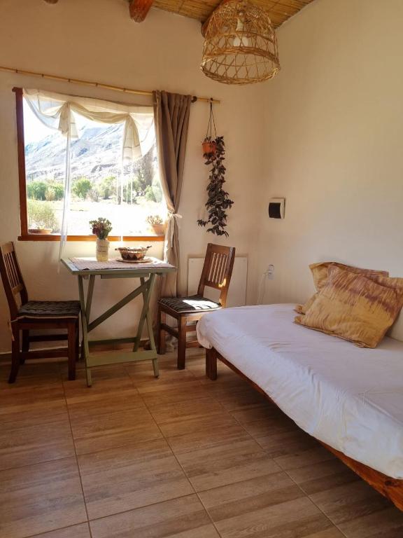 a bedroom with a bed and a table and chairs at Cabaña La Marcelina in Tilcara